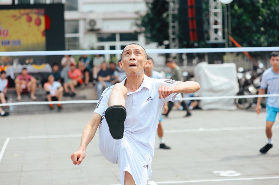 Elderly men playing kick volleyball outdoors on a sunny day.